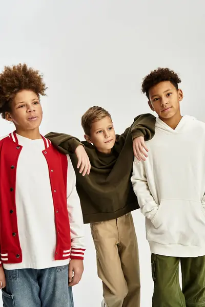 Tres adorables niños pequeños están disfrutando de la compañía de los demás, vestidos con un atuendo vibrante de moda. - foto de stock