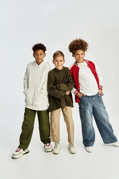 Tres chicos lindos muestran sus estilos únicos en trajes vibrantes, disfrutando de momentos alegres juntos. - foto de stock