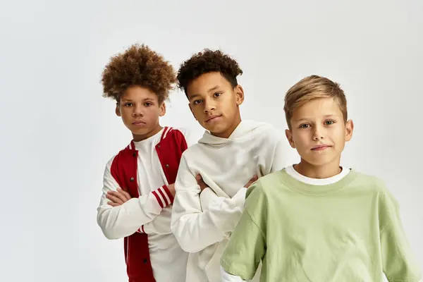 Tres chicos adorables muestran su sentido único de la moda mientras están de pie juntos en amistad. - foto de stock