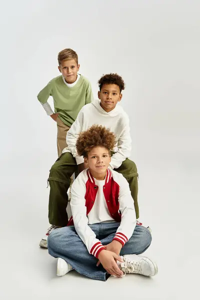 Tre adorabili ragazzi che indossano abiti alla moda celebrano l'amicizia con risate e gioia. — Foto stock