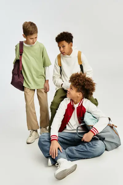 Tres adorables chicos disfrutan de la compañía de los demás mientras muestran sus estilos modernos y vibrantes. - foto de stock