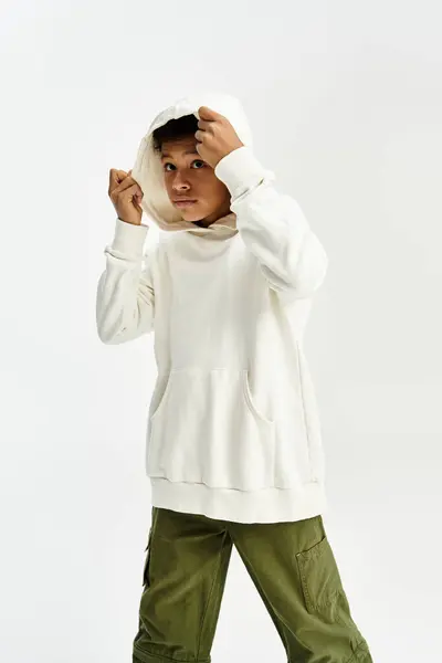 Adorable jeune garçon pose élégamment dans un sweat à capuche confortable et pantalon à la mode, exsudant charme et confiance. — Photo de stock