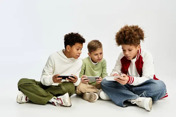 Three little boys in stylish outfits bonding over a fun gaming experience together. — Stock Photo