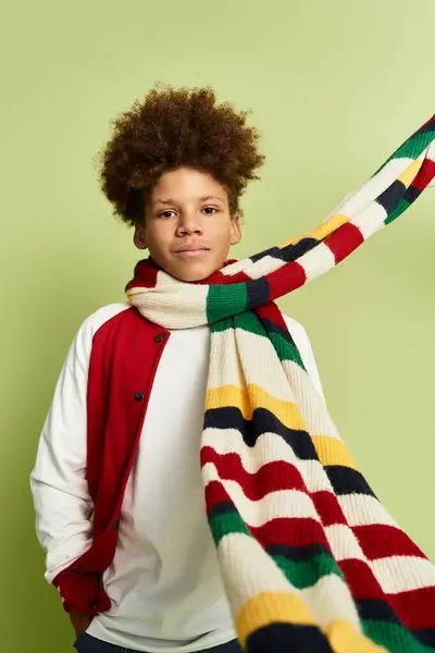 Brillantemente vestido niño se para con confianza con una bufanda de colores que fluye en un entorno verde animado. - foto de stock