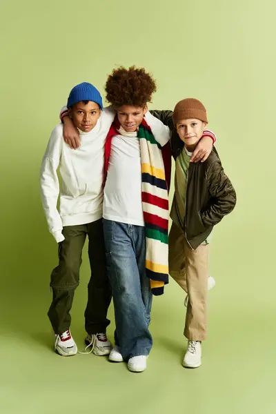 Tres niños pequeños vestidos con trajes de moda y coloridos, comparten un momento alegre juntos. - foto de stock