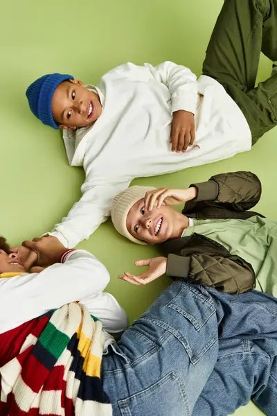 Three adorable boys lie on a colorful surface, sharing laughter and stylish outfits with joy. — Stock Photo