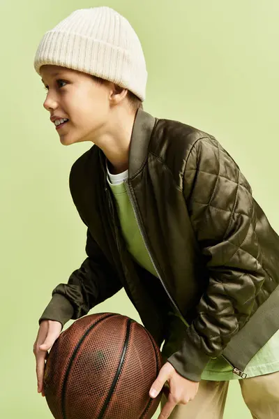Young boy wearing trendy attire holds a basketball, ready for an exciting game and fun activity. — Stock Photo