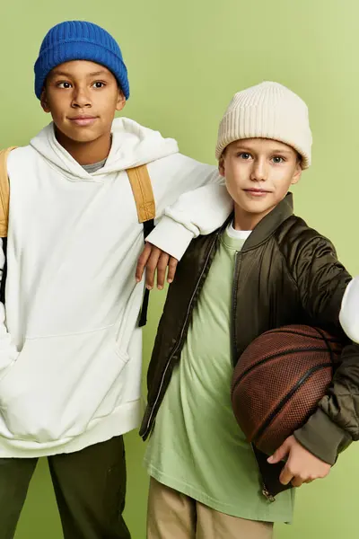 Dos adorables niños con trajes elegantes disfrutan de la compañía de los demás mientras sostienen un balón de baloncesto. - foto de stock
