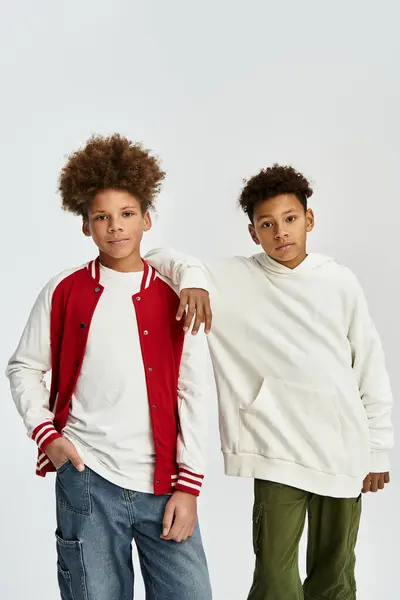 Dos chicos adorables vestidos con trajes vibrantes comparten un momento de amistad y estilo. - foto de stock
