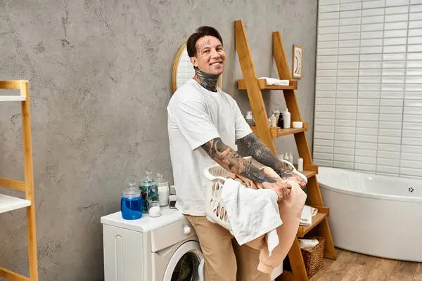 Bello giovane uomo sorride calorosamente mentre organizza il bucato nel suo comodo spazio domestico. — Foto stock