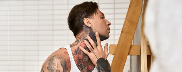 Gentleman tatoué s'engage dans l'auto réflexion tout en étant entouré d'un espace chaleureux et accueillant à la maison. — Photo de stock