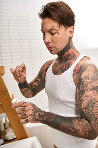 Tätowierte junge Mann genießt einen gemütlichen Moment zu Hause, in einer kreativen und persönlichen Aktivität engagiert. — Stockfoto