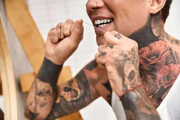 In einem gemütlichen Zuhause legt ein tätowierter Mann Wert auf zahnärztliche Versorgung und zeigt Selbstpflege und Komfort. — Stockfoto