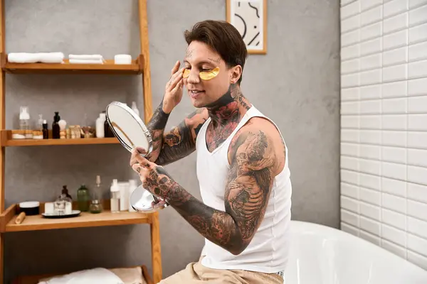 A tattooed young man enjoys a skincare mask in a cozy moment at home. — Stock Photo