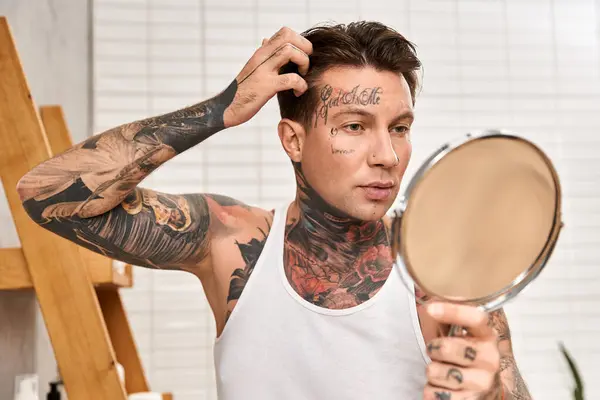 Tätowierter Mann überprüft sein Aussehen im Spiegel, während er einen gemütlichen Moment zu Hause genießt. — Stockfoto