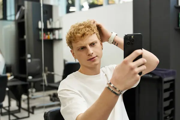 Young man assesses his hairstyle while taking a selfie in a trendy beauty salon. — Stock Photo