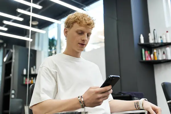 Client relaxes in a stylish beauty salon, browsing the latest fashion trends on a smartphone. — Stock Photo