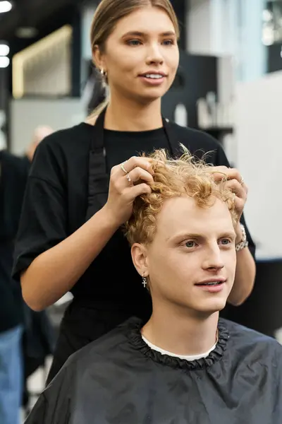 A stylist enhances a clients curls, showcasing modern beauty trends in a chic salon. — Stock Photo