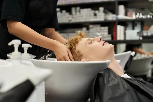 Client receives a soothing hair wash in a chic salon while embracing current beauty fashions. — Stock Photo