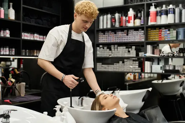 Skilled styist offers a refreshing wash to a client in a contemporary beauty salon setting. — стоковое фото