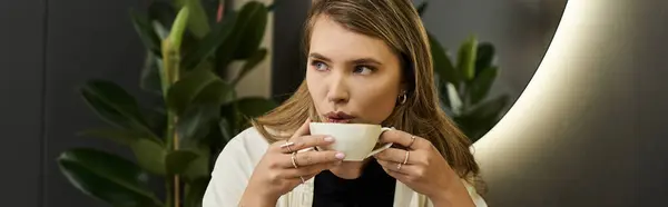 A young woman enjoys a steaming drink while surrounded by beauty trends and greenery. — Stock Photo