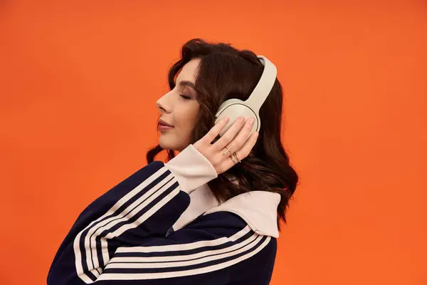 A young woman models a stylish skirt and jacket while listening to music. — Stock Photo