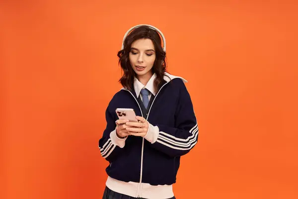 Fashion-forward young woman checks her phone while sporting a trendy outfit in a studio setting. — Stock Photo