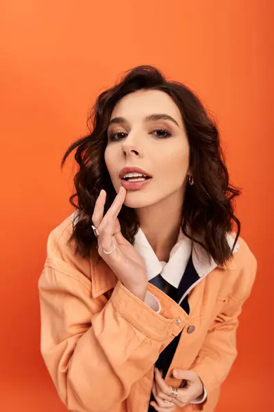 A stylish young woman poses confidently in a chic skirt and jacket amid warm orange tones. — Stock Photo