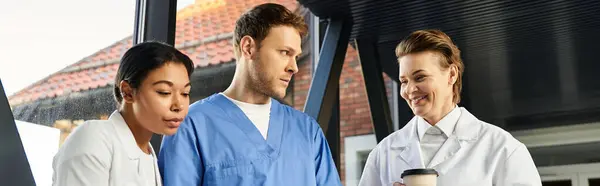 Three diverse doctors engage in a discussion, showcasing teamwork in a contemporary hospital, banner - foto de stock