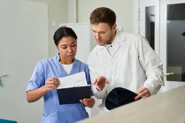 Two dedicated doctors analyze an MRI scan together, showcasing teamwork in healthcare. — Stockfoto