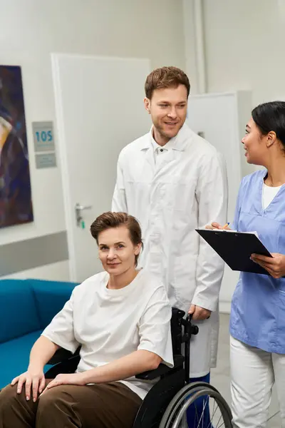 Handsome doctor and African American nurse assist a female patient in a wheelchair before her MRI. — Stock Photo