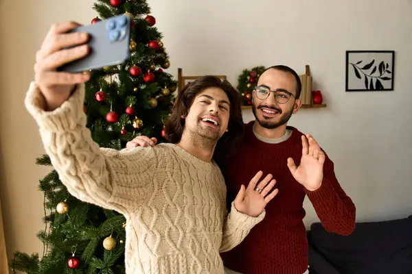 Двое мужчин захватывают радостное селфи украшенной елкой, делясь любовью дома. — стоковое фото