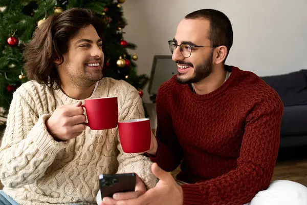 Двое мужчин разделяют радостные моменты дома, наслаждаясь праздничными напитками и друг друга компании. — стоковое фото
