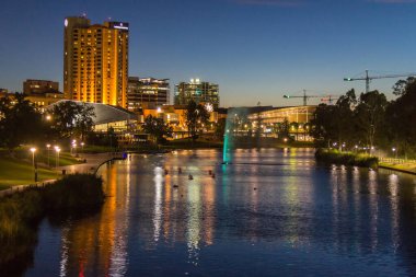 Adelaide şehri CBD, Torrens nehri boyunca parktaki yaya köprüsünden gün doğumunda görülüyor.