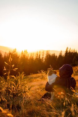 Köpek ve insan gün doğumunda dağlarda