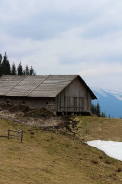 Dağların ortasında çatısı olan küçük ahşap bir ahır manzarası