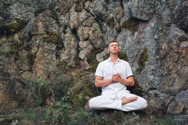the guy meditates in the lotus position on the rock