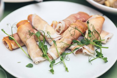 bacon rolls stuffed with vegetables, garnished with microgreens.