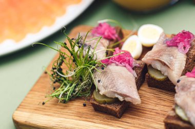 Black bread sandwich with herring, pickled cucumber and microgreens.