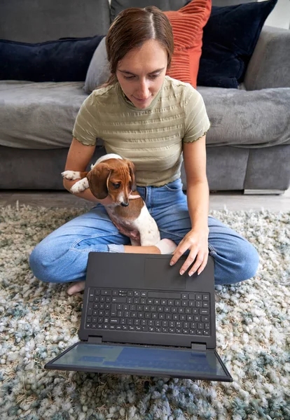 Молодая Женщина Сидящая Полу Перед Диваном Дома Работающая Ноутбуке Собакой — стоковое фото