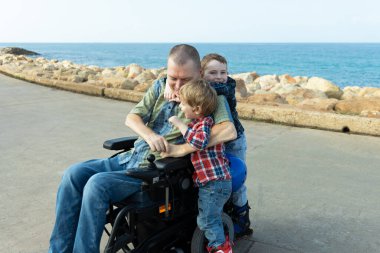 Engelli adam deniz kenarında küçük çocuklarla paten kayıyor.
