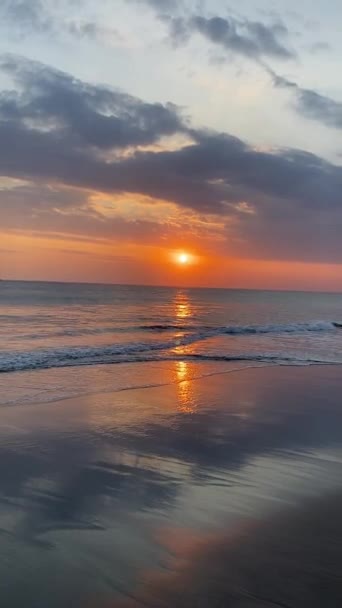 朝の波と雲でビーチに日の出 バリの平和なビーチに囲まれた黄金の日没の穏やかな美しさでリラックスしてください 平和な時代が待ち受けている — ストック動画