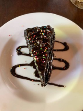 Yemek blogları, tatlı menüleri, pastane web siteleri, sosyal medya paylaşımları ve tarif kartları için uygun çikolata soslu bir tabak..