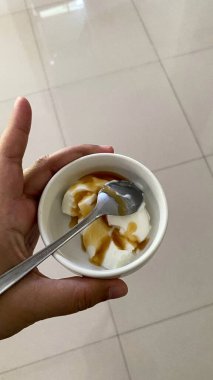 Elinde bir kase yoğurt ve kaşık tutan kişi sağlıklı beslenme blogları, yemek tasarımı ve sosyal medya içeriği için idealdir..