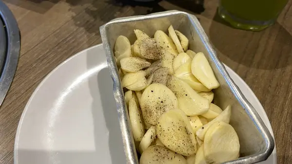 Pan of sliced potatoes on a plate, ideal for food blogs, restaurant menus, recipe websites, cooking tutorials, or kitchenrelated designs.