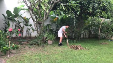 Elinde süpürgeyle çimlerin üzerinde duran bir adam var. Adam elinde süpürgeyle çimenlerde duruyor. Çevre temizliği, bahçe bakımı, açık hava bakımı, sürdürülebilirlik, koruma, peyzaj ve park bakımı için elverişli.