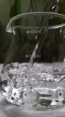 Cam deney şişesine su dökülüyor. Bir cam şişenin içine dökülen suyun yakın plan görüntüsü, 400 ml 'ye kadar dolduruluyor..