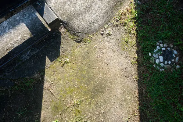 Çimen ve toprak üzerine paralel gölge çizgilerinin yakın çekimi soyut bir desen oluşturur..