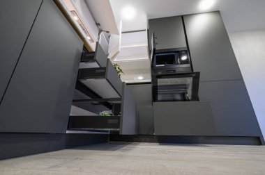 Closeup details of showcase interior of modern simple dark grey and white kitchen, drawers retracted, low angle view