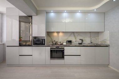 Interior of well designed modern trendy white kitchen, front view